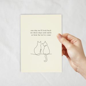 An ivory coloured card with a lineart of cats sitting next to each other.